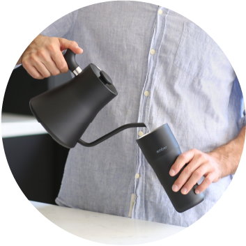 Man Pours water into Travel Mug from a black kettle